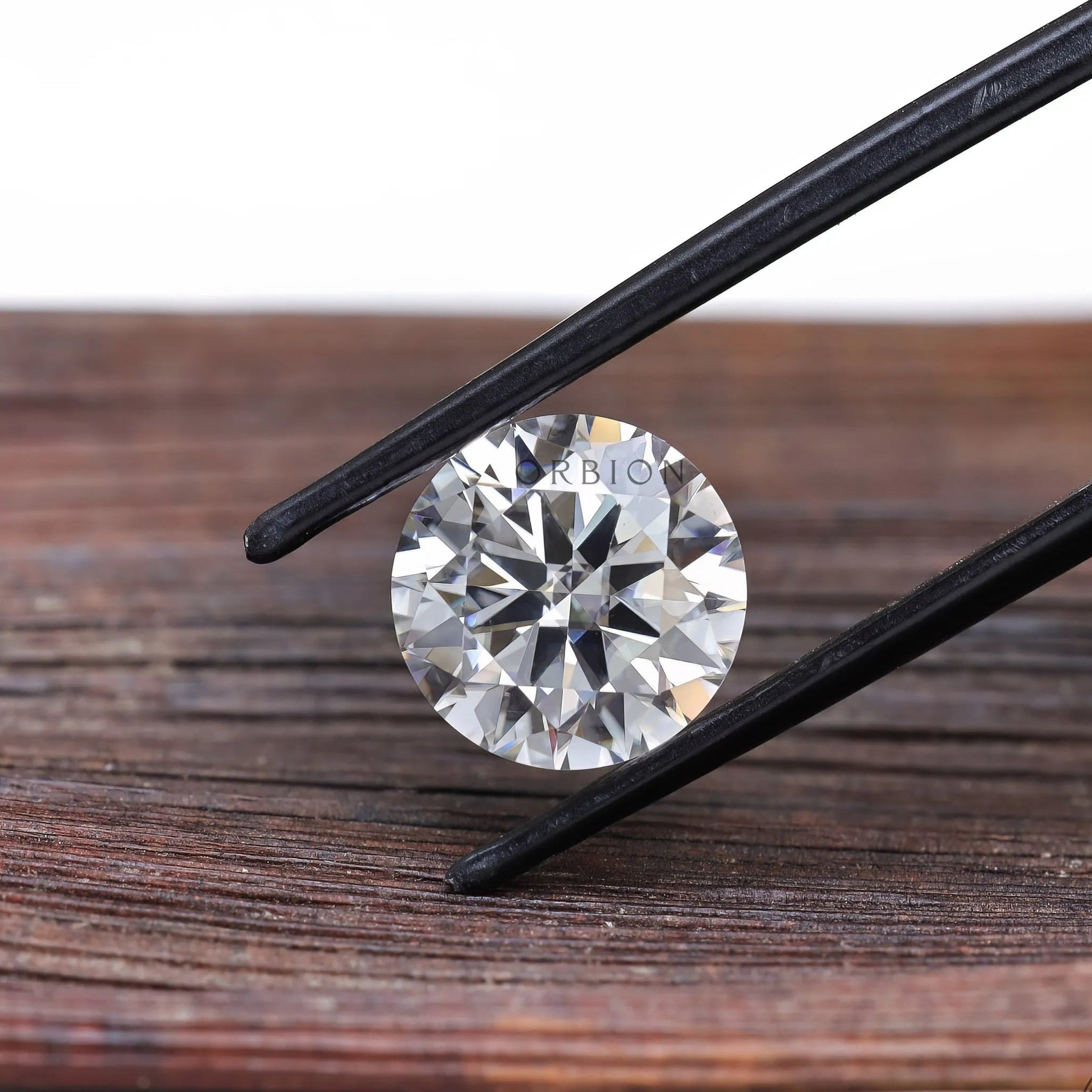 Round brilliant moissanite held with tweezers