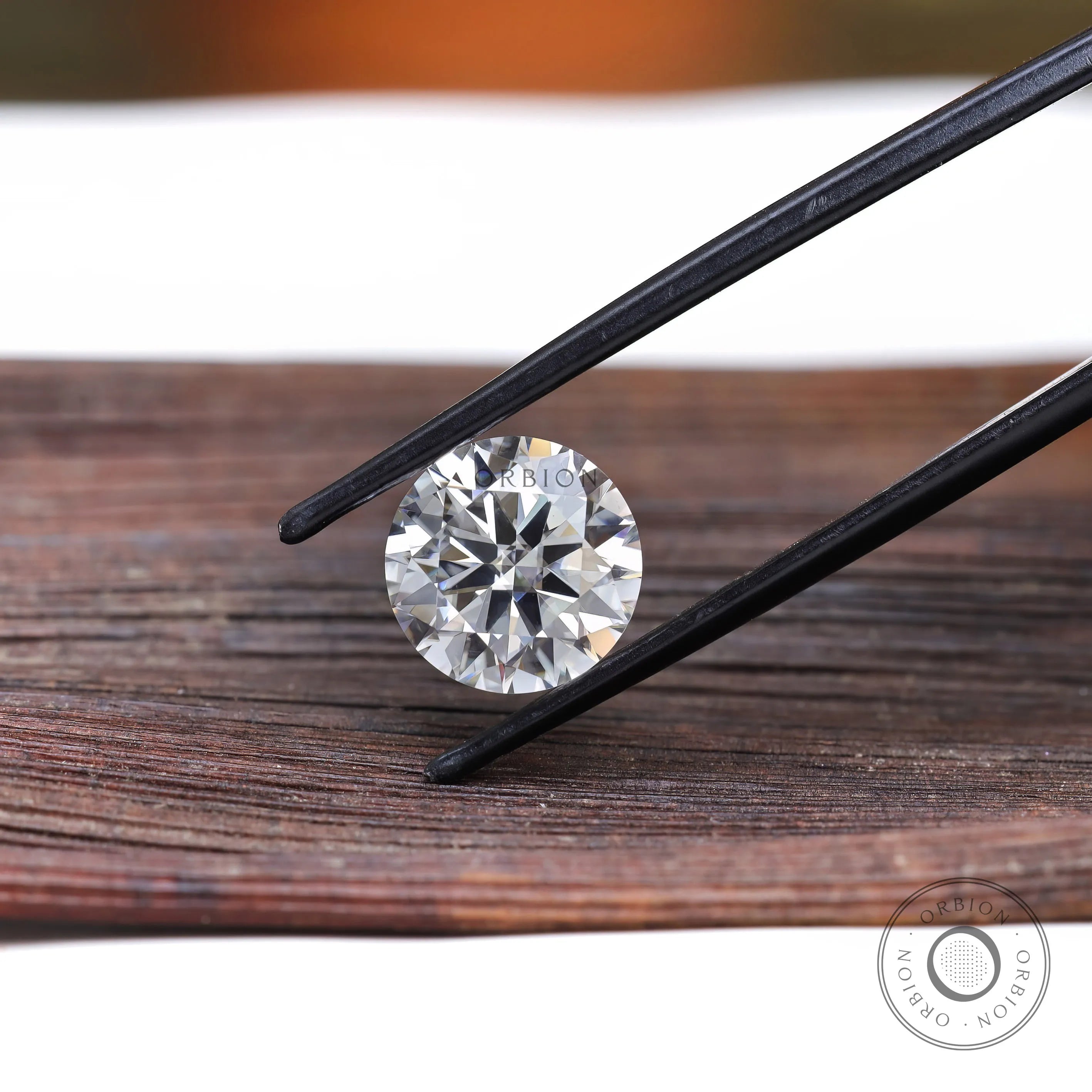 Round brilliant moissanite held with tweezers