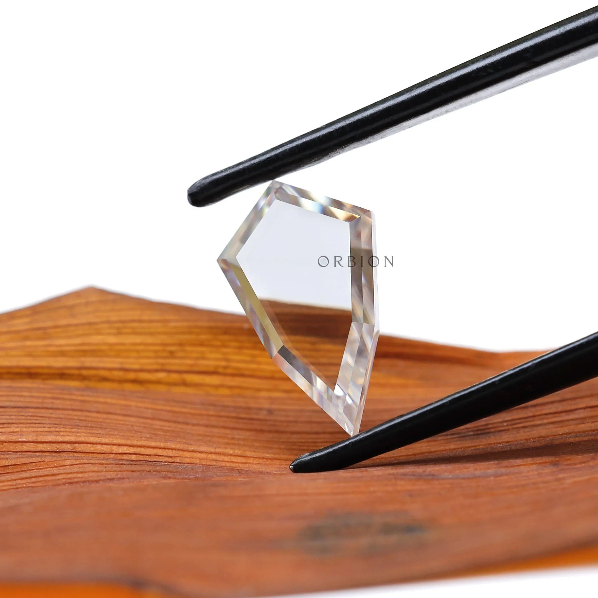 Shield moissanite held in tweezers showing modern silhouette