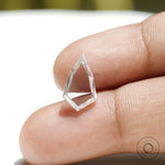 Shield shaped moissanite placed on fingertip showing transparency
