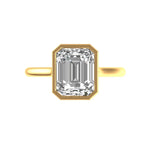 Emerald cut bezel set solitaire ring in 14k yellow gold