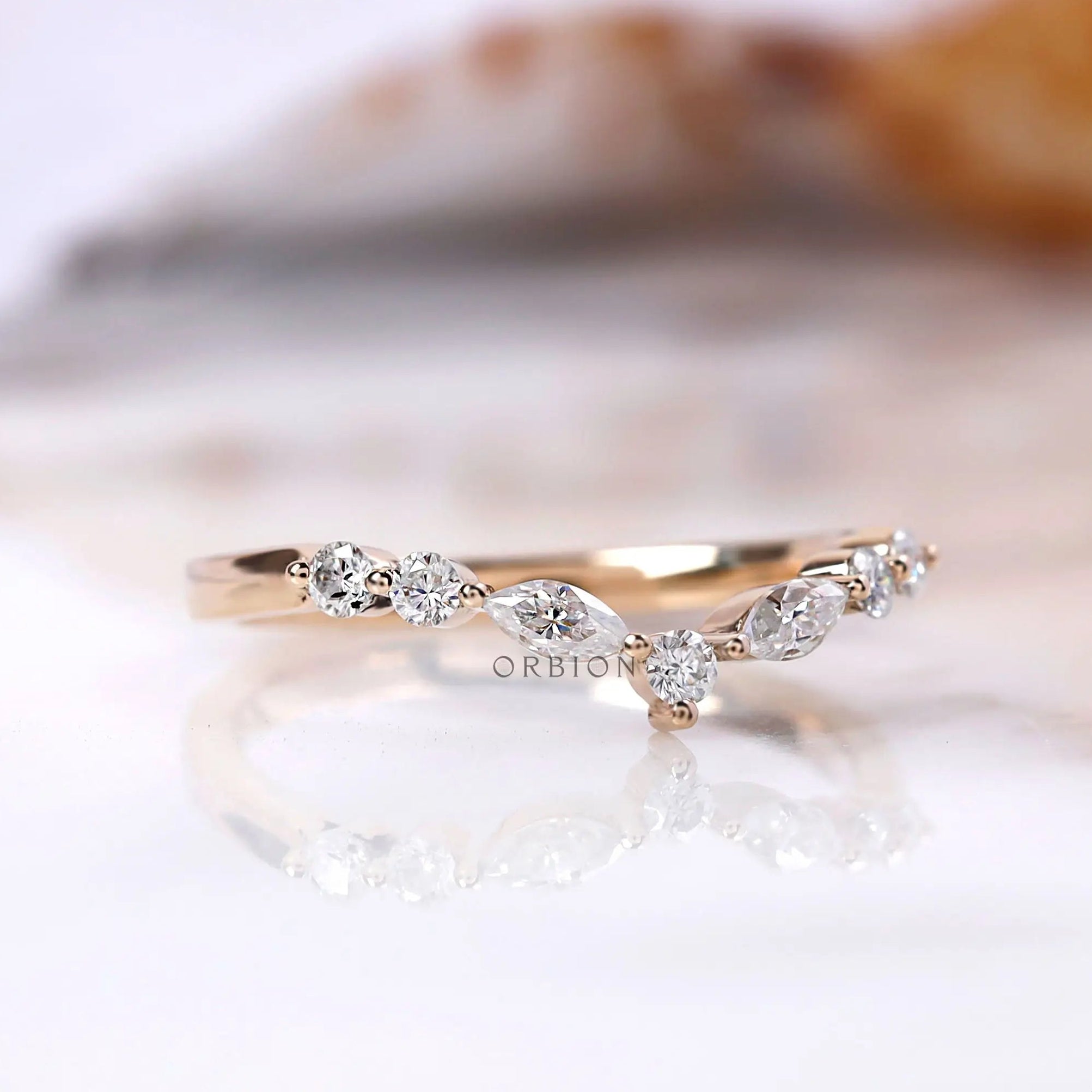 Angled view of marquise and round moissanite chevron ring