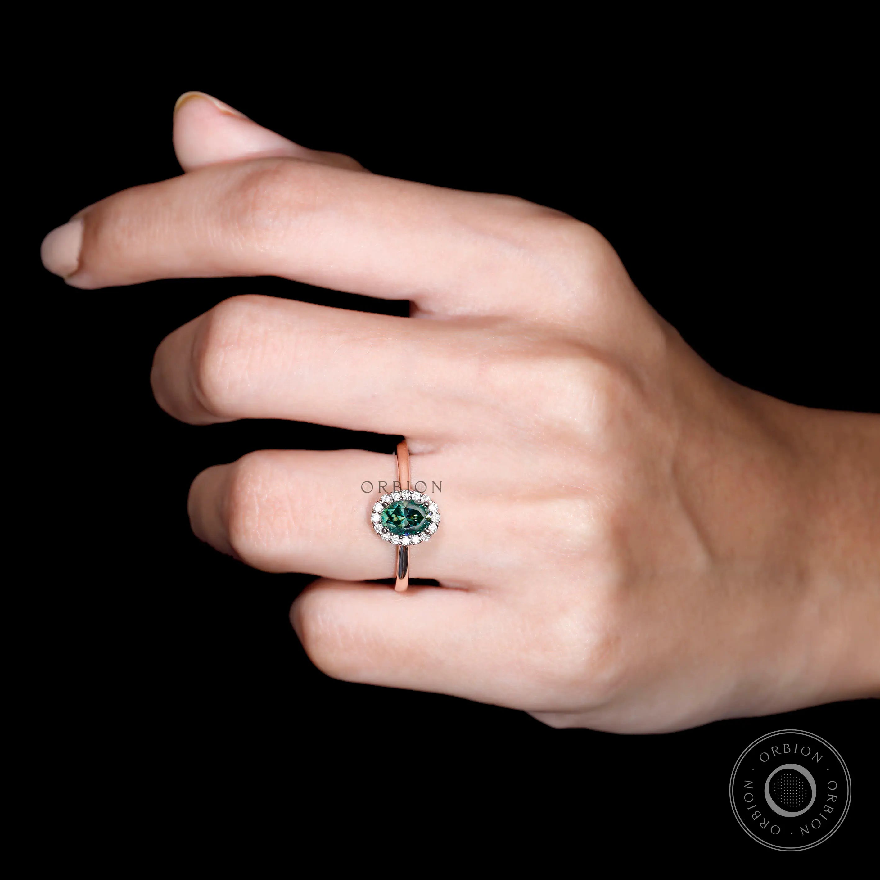 Oval blue green moissanite halo ring in 10K rose gold on hand