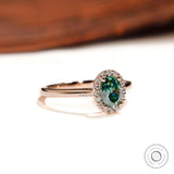 Side profile of oval halo blue green moissanite ring in rose gold