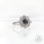 Angled front view showing black center with bright moissanite halo cluster.