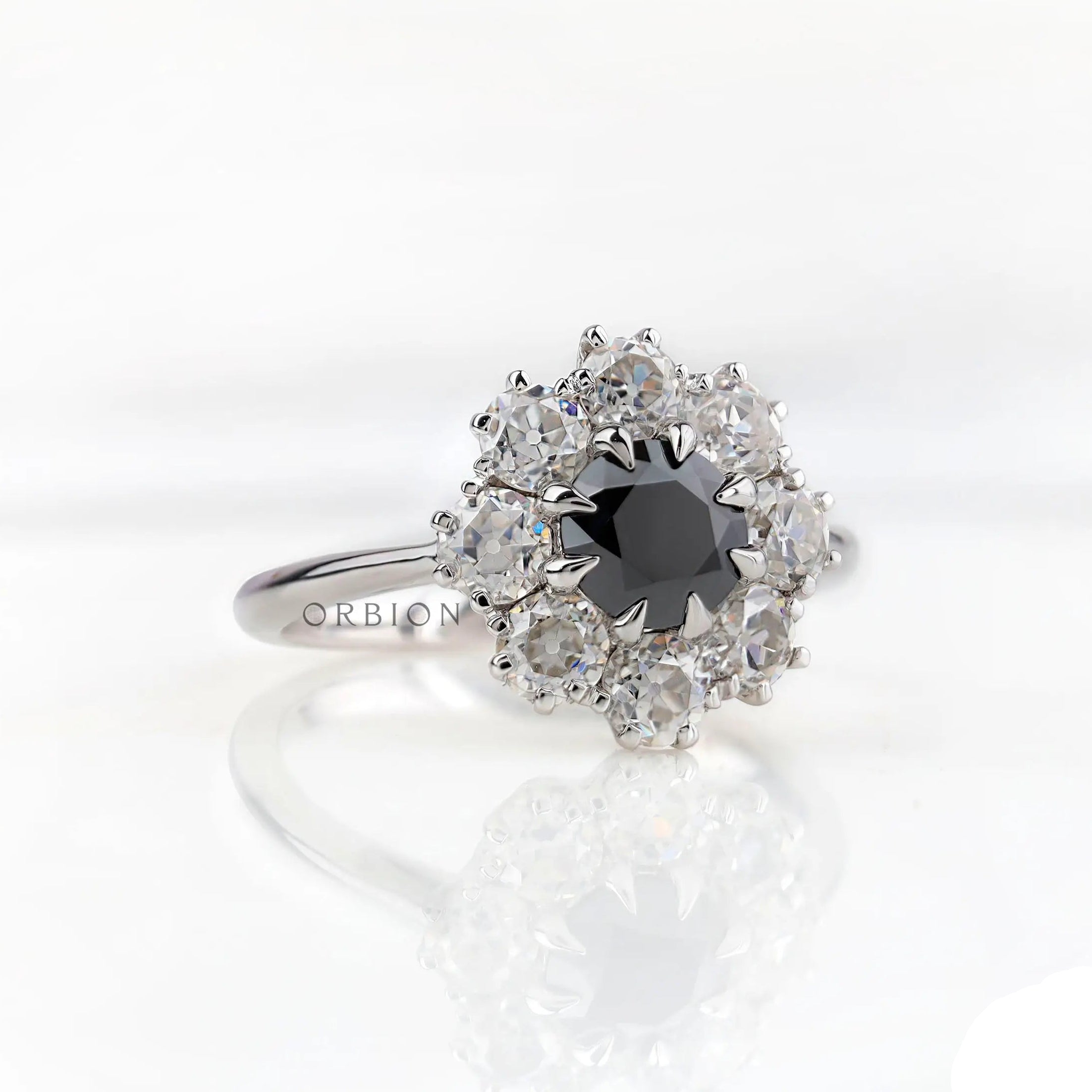 Angled front view showing black center with bright moissanite halo cluster.
