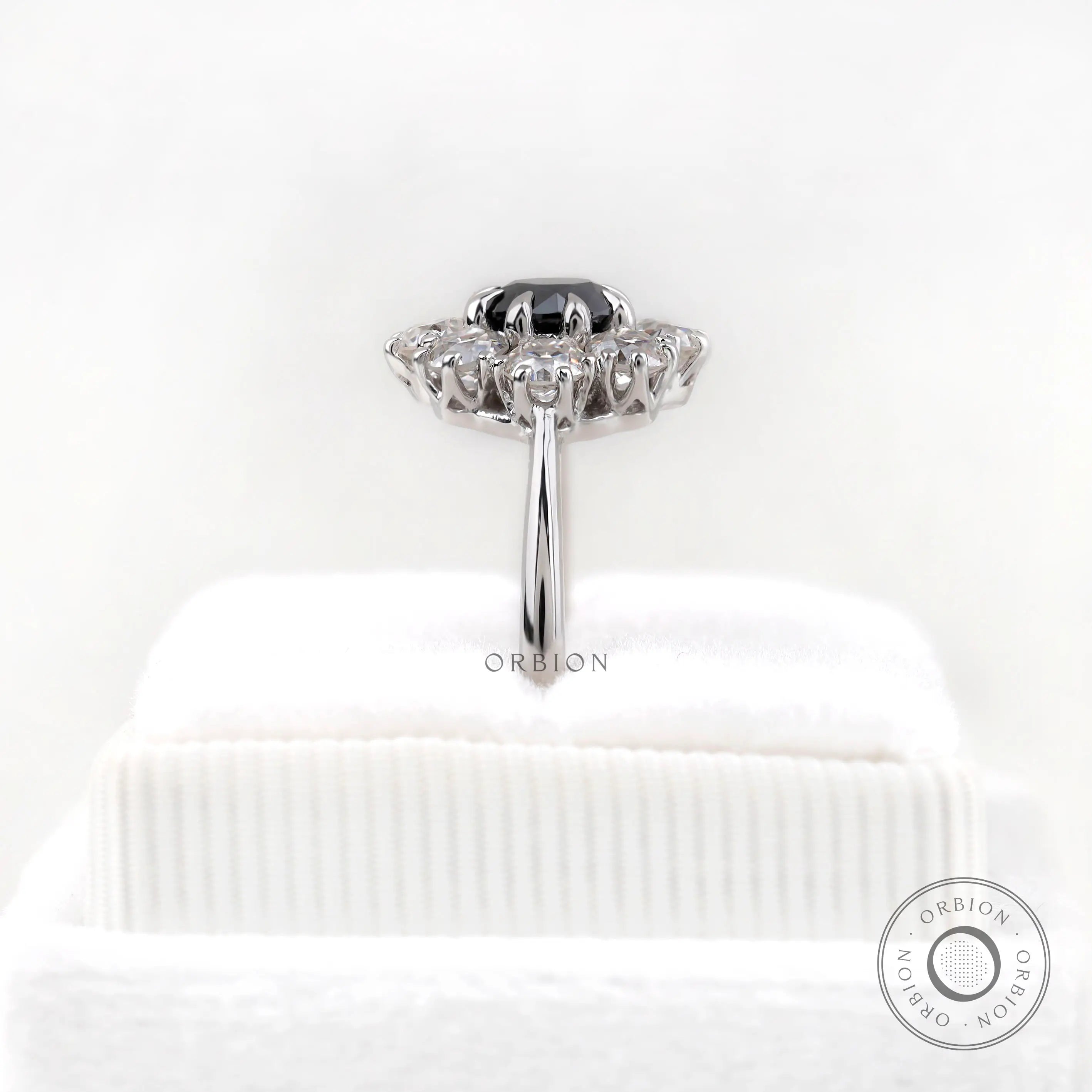 Rear side view on stand showing halo thickness and polished white gold shank.