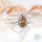 Profile view of pear-shaped Moissanite halo ring, with a unique band design in white gold.