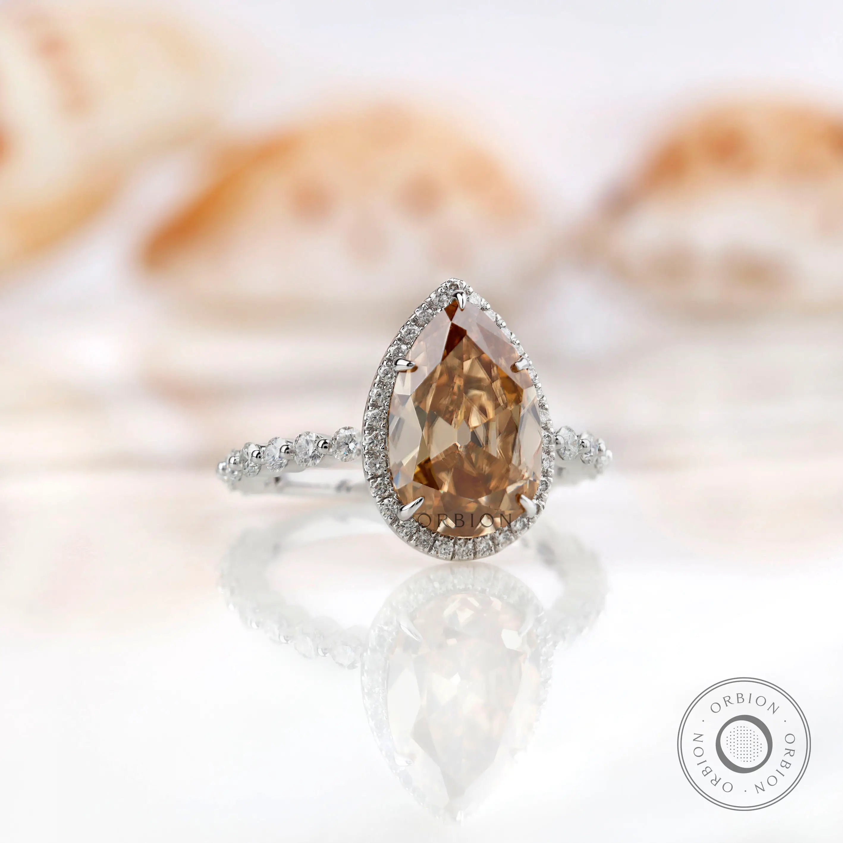 Profile view of pear-shaped Moissanite halo ring, with a unique band design in white gold.