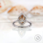 Pear Moissanite halo ring showing stunning round brilliant side stones in white gold setting.