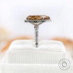 Pear-shaped Moissanite halo ring with sparkling round side stones in white gold.