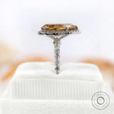 Pear-shaped Moissanite halo ring with sparkling round side stones in white gold.