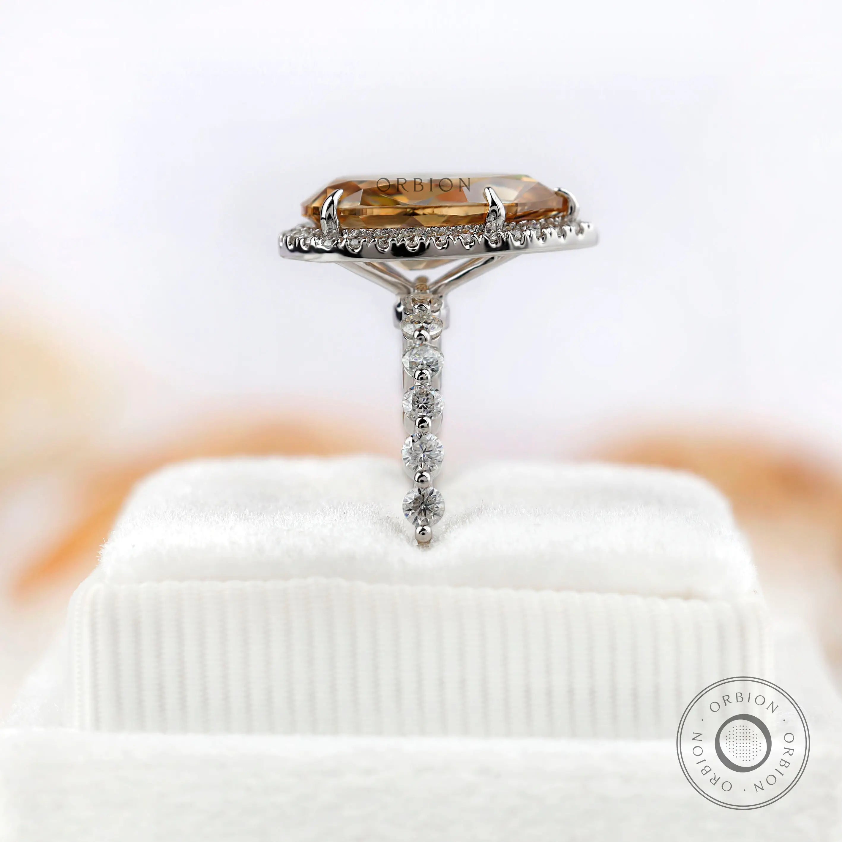 Pear-shaped Moissanite halo ring with sparkling round side stones in white gold.