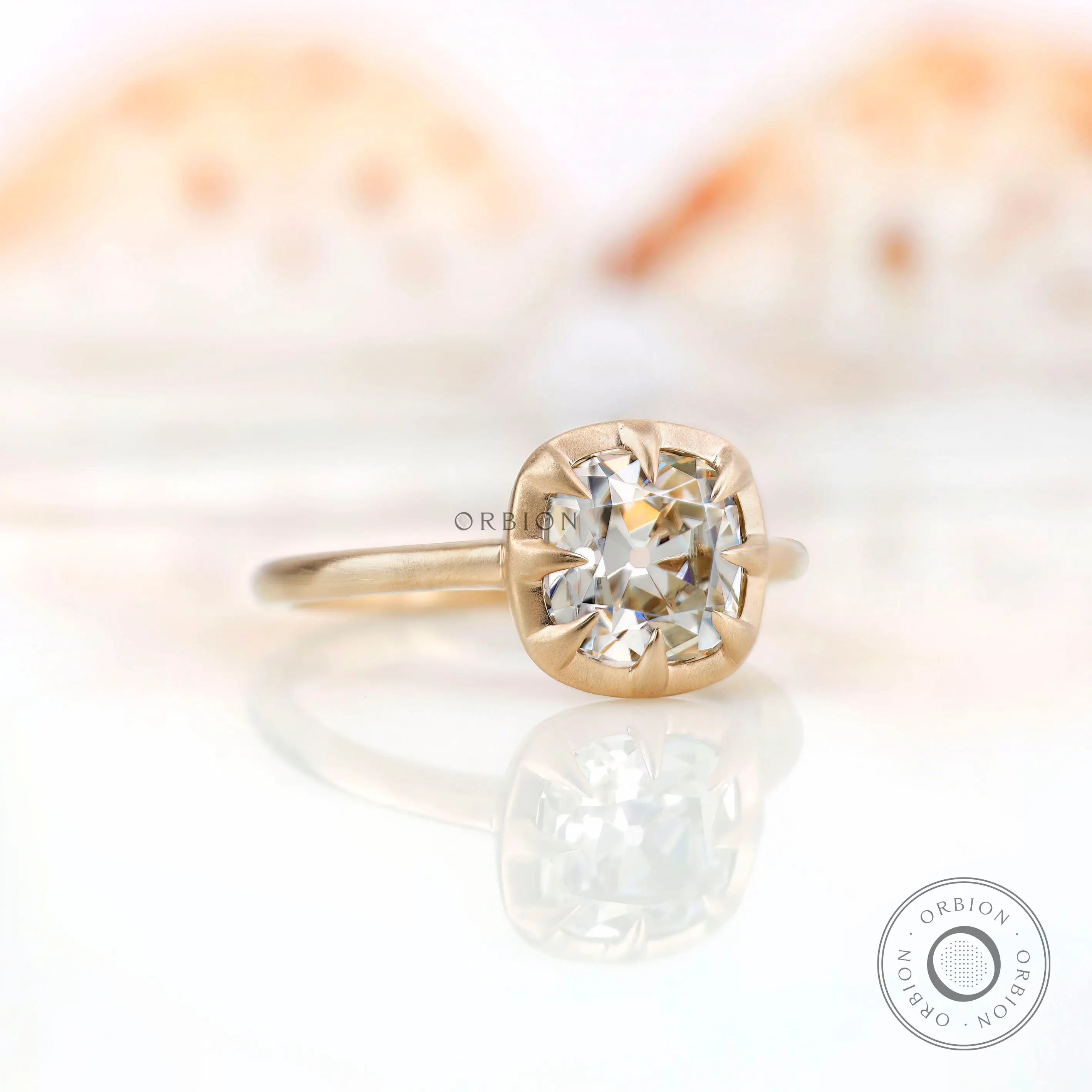 Angled side view of the square cushion GHI moissanite solitaire bezel set engagement ring in yellow gold.