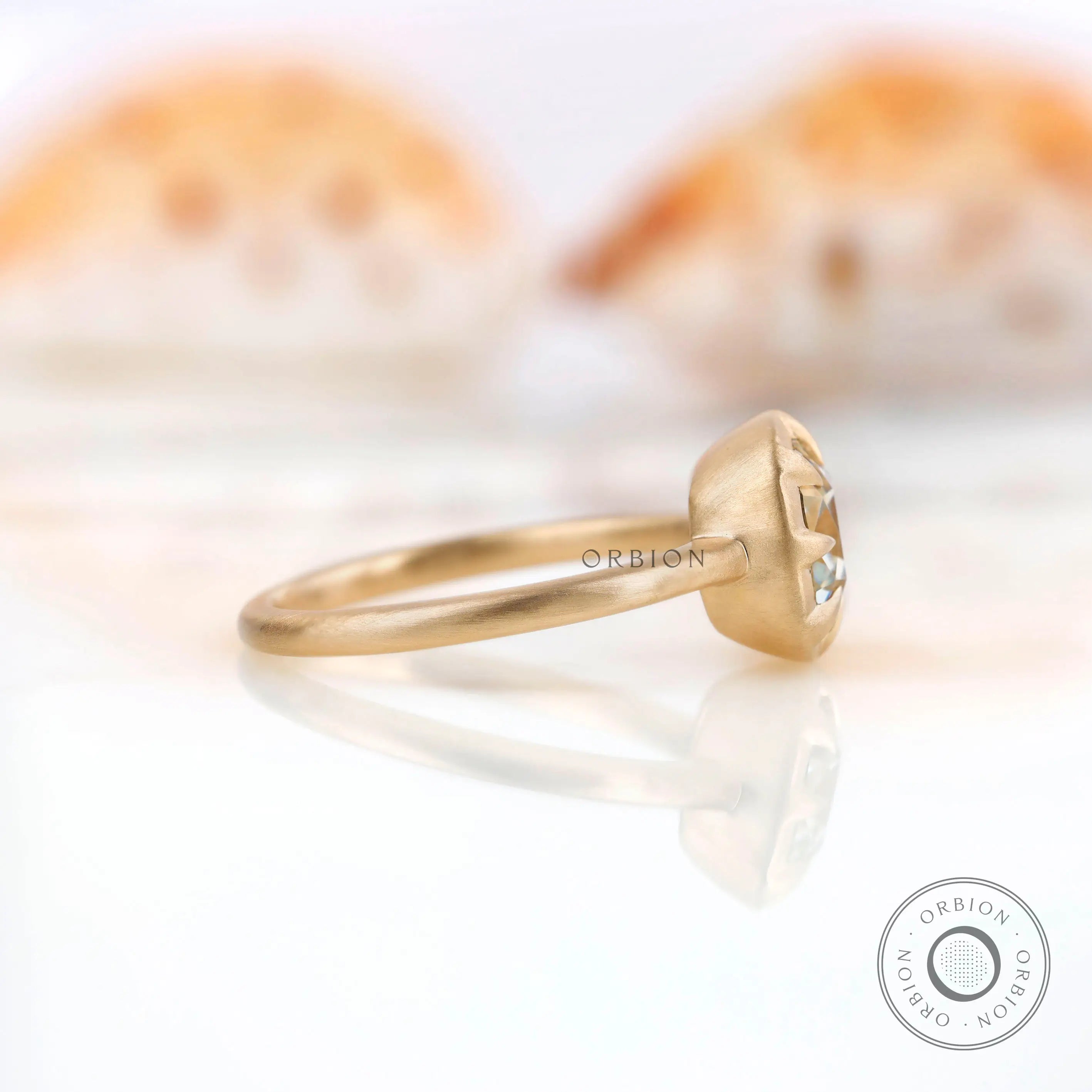 Side profile highlighting the bezel setting and matte yellow gold band of the square cushion GHI moissanite ring.