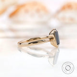 Side view of emerald cut black green moissanite ring in yellow gold