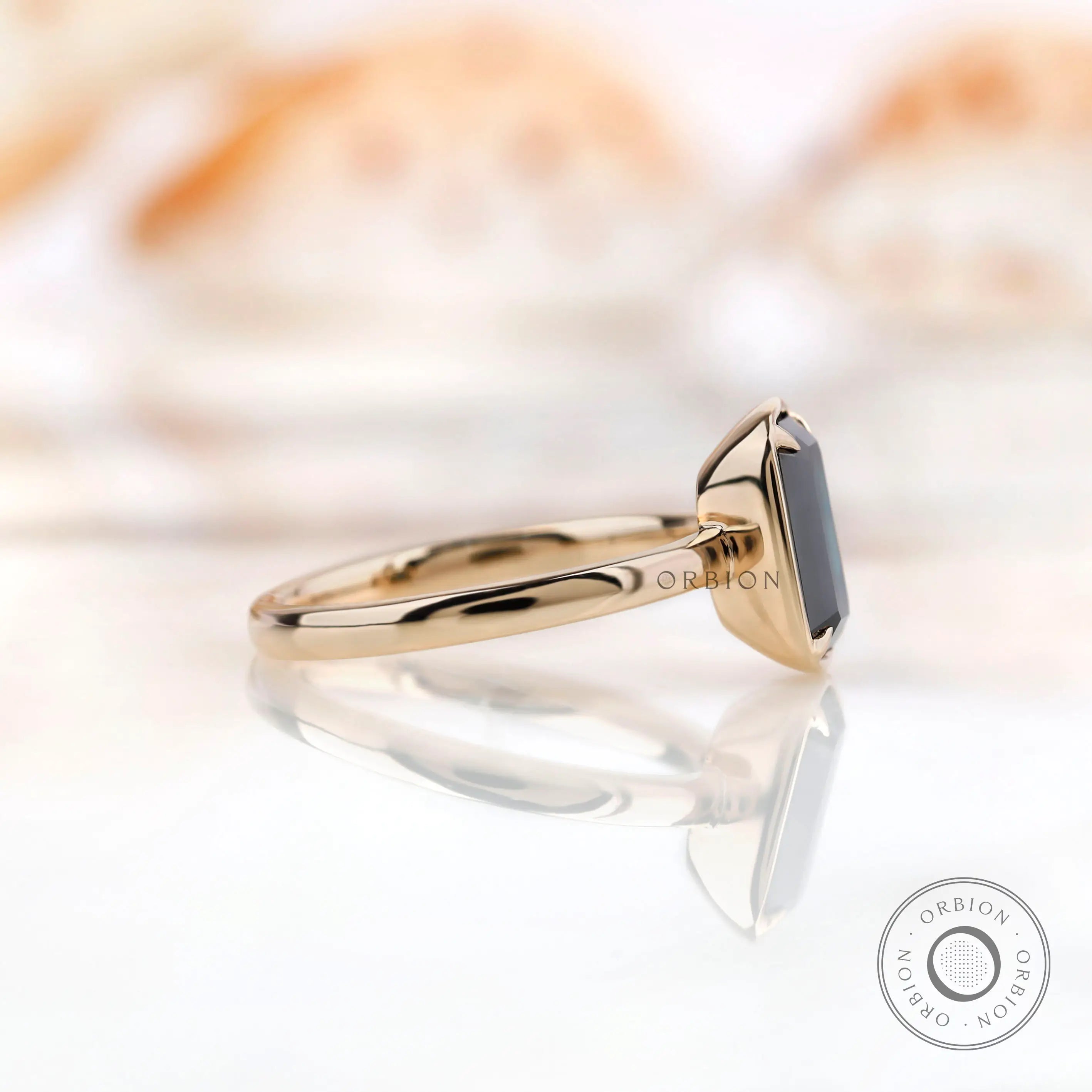 Side view of emerald cut black green moissanite ring in yellow gold