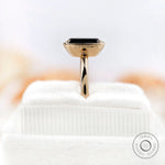 Close-up side view of solitaire emerald cut black green moissanite ring