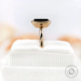 Close-up side view of solitaire emerald cut black green moissanite ring