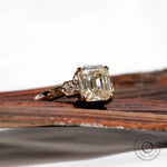 Another angle of the Asscher cut center stone Moissanite engagement ring with round Moissanite side stones, set in 10K yellow gold.