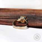 Image showing the Asscher cut Moissanite center stone with round Moissanite side stones, in a three-stone engagement ring set in 10K yellow gold.