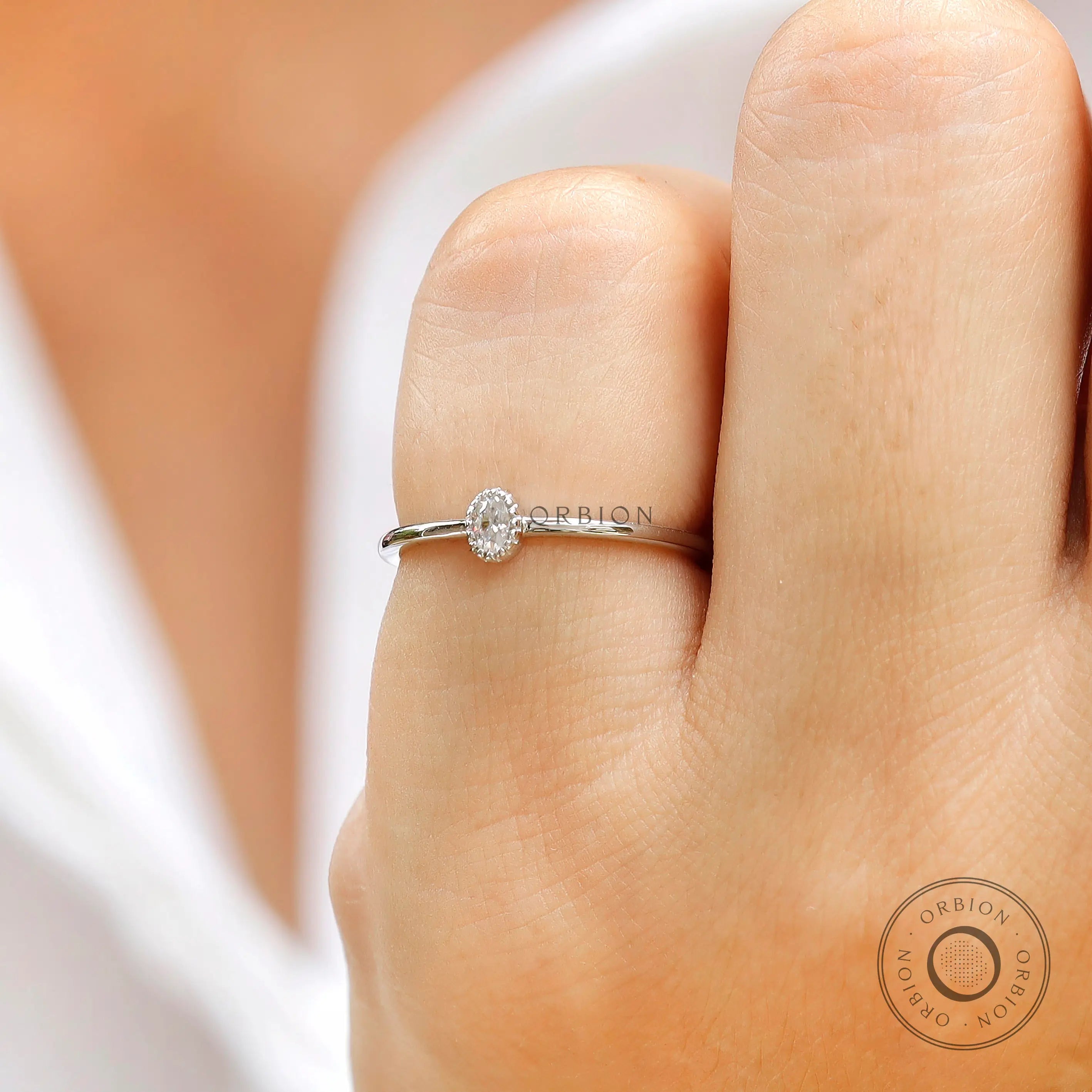 Petite oval moissanite delicate ring on finger