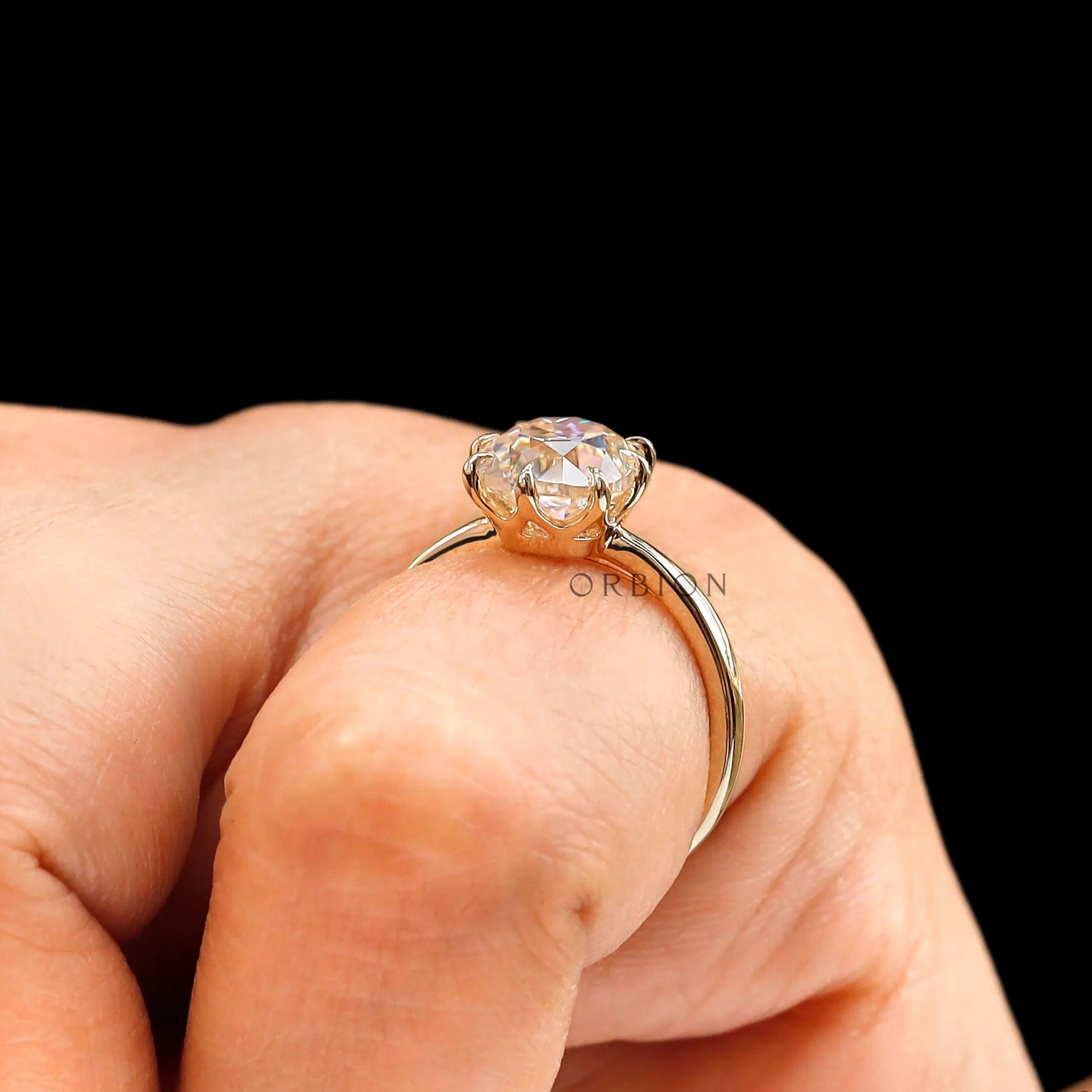Close up on finger of elongated cushion old mine cut solitaire ring in yellow gold