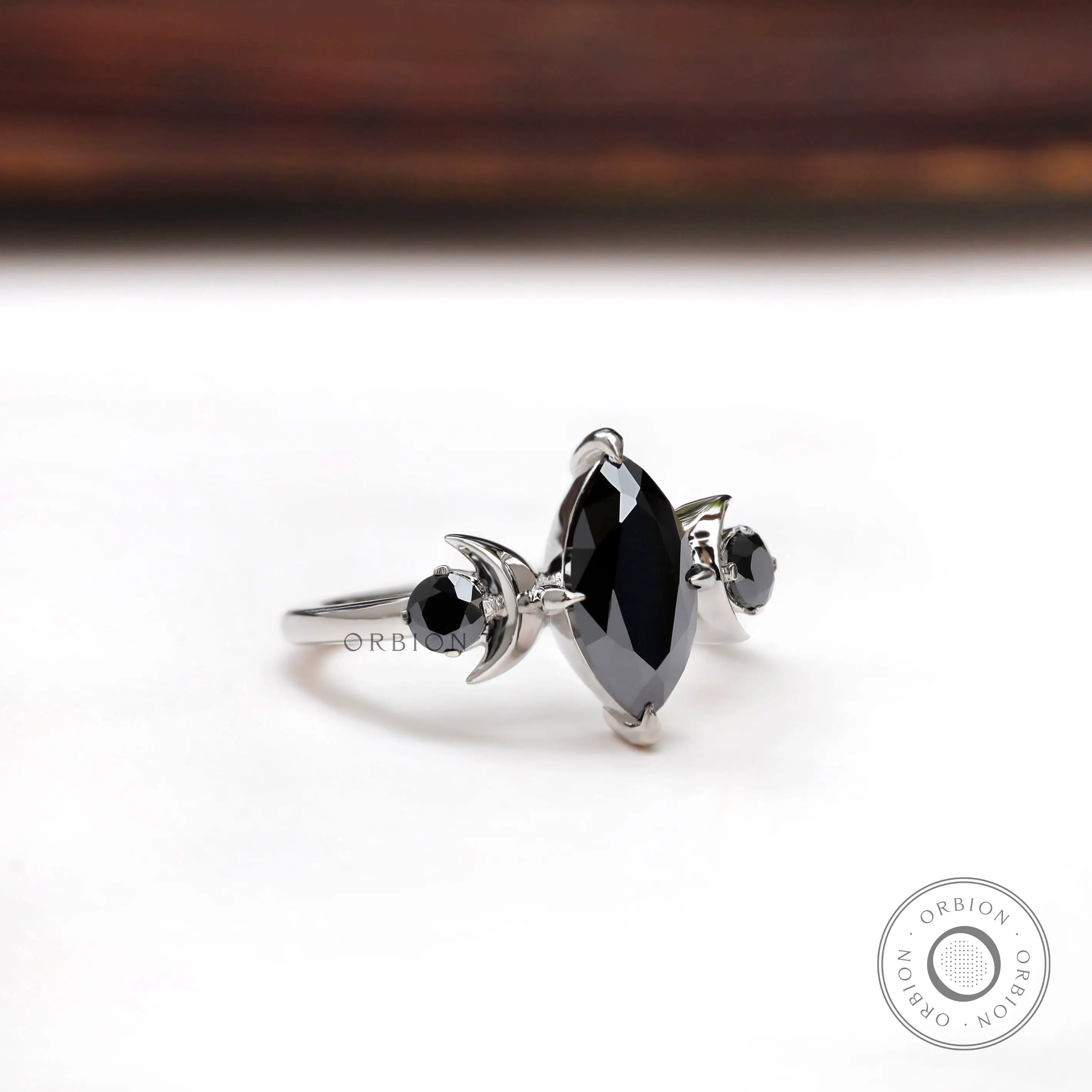 Close up of black marquise moissanite with round side stones
