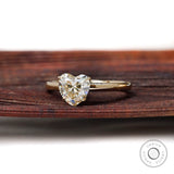 Angled front view heart solitaire ring on textured wooden surface
