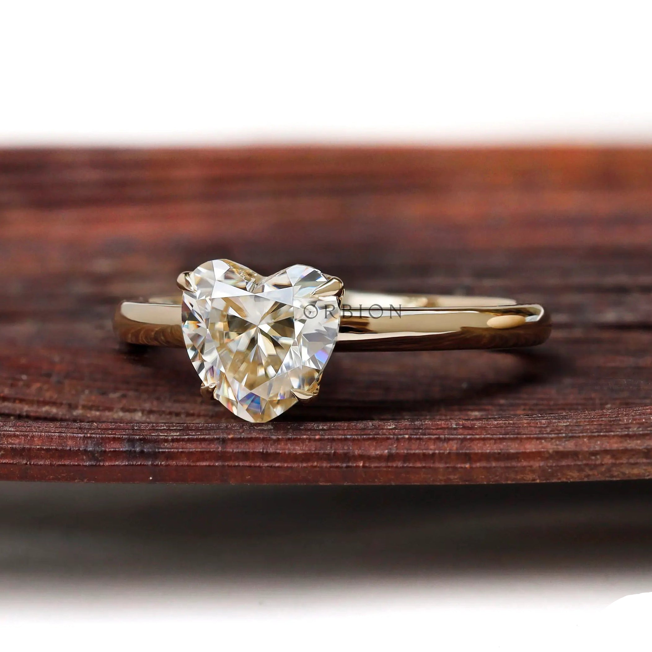 Angled front view heart solitaire ring on textured wooden surface
