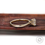 Side profile tulip setting heart ring displayed on brown wooden background