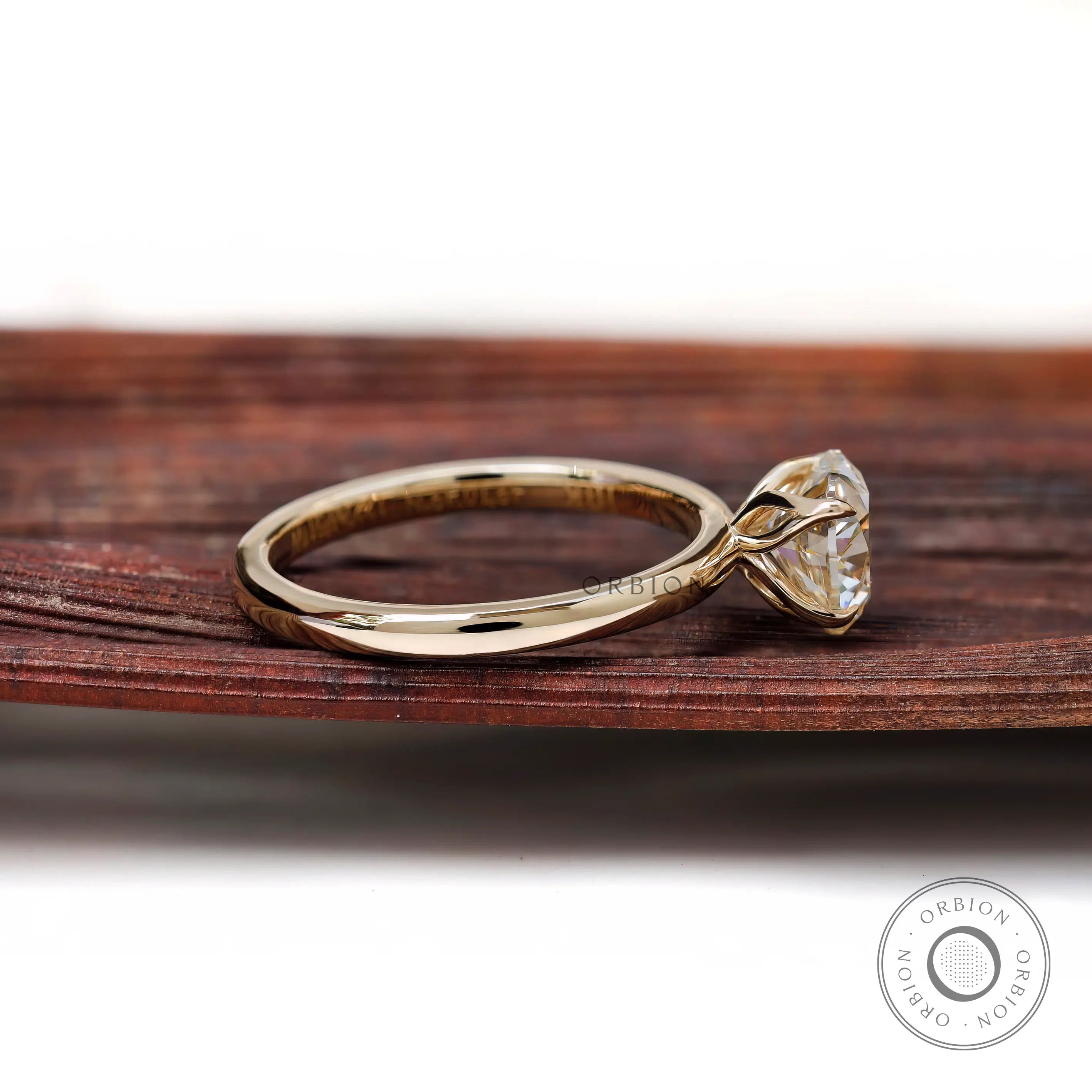 Side profile tulip setting heart ring displayed on brown wooden background