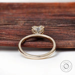 Rear view heart solitaire ring resting on rustic wood backdrop