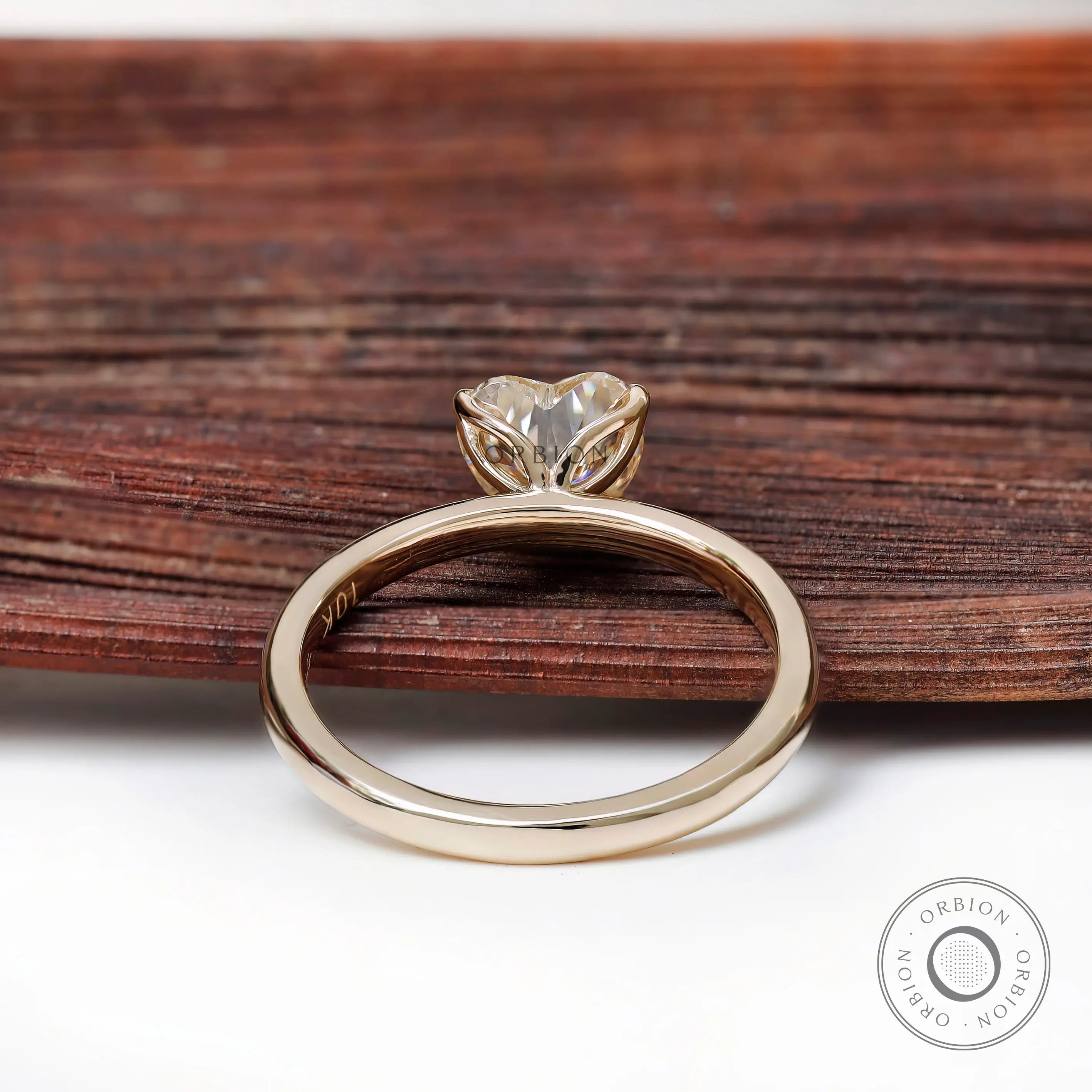 Rear view heart solitaire ring resting on rustic wood backdrop