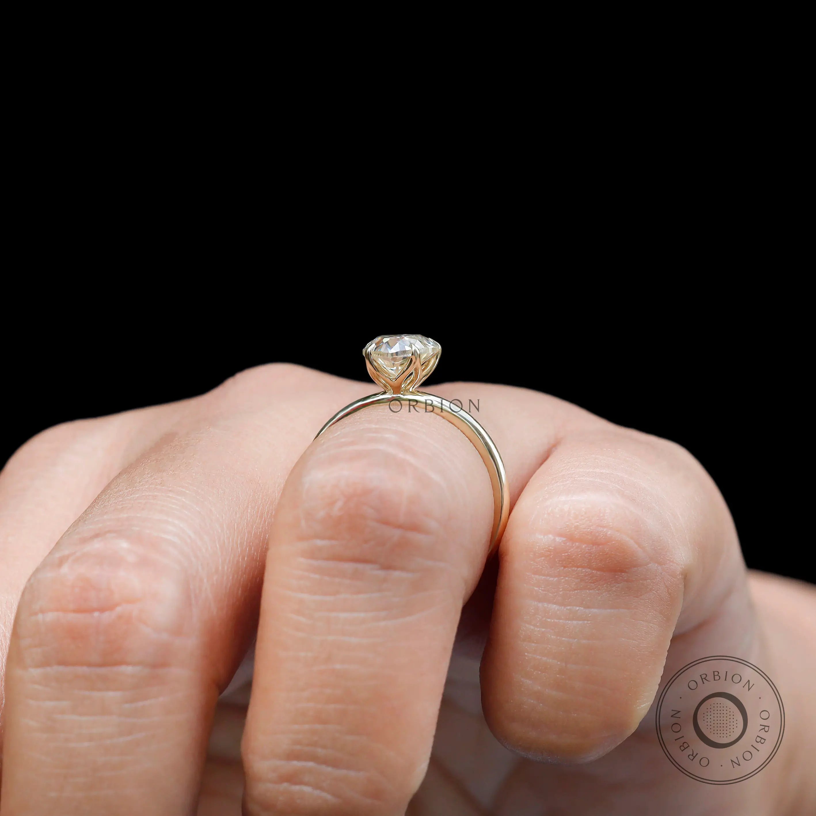Side profile heart solitaire ring worn on hand with black background