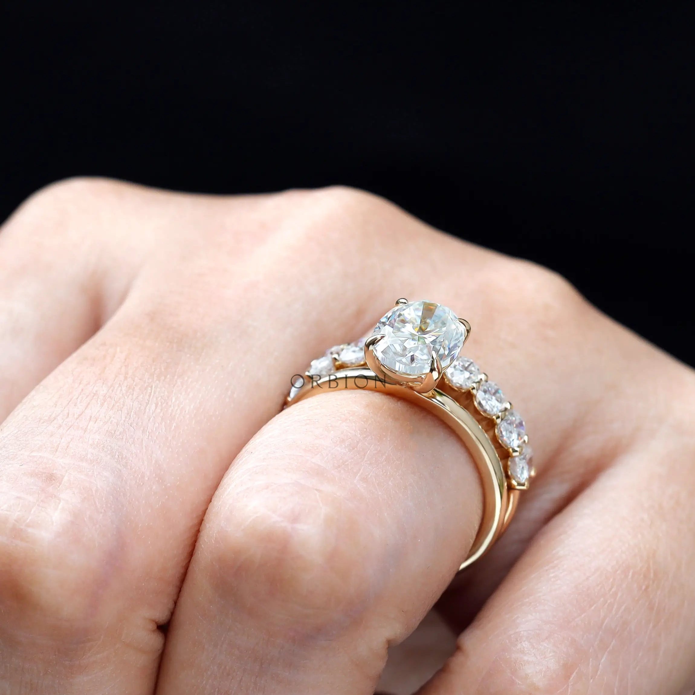 On hand view showing oval solitaire and stack band
