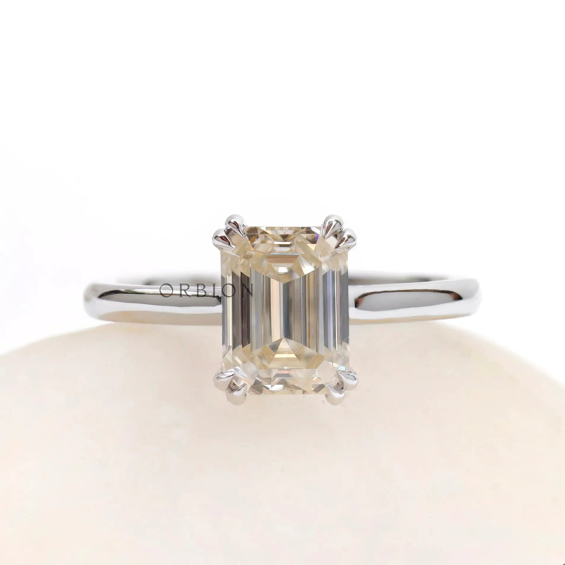 Front view emerald cut moissanite solitaire ring on white stone in white gold