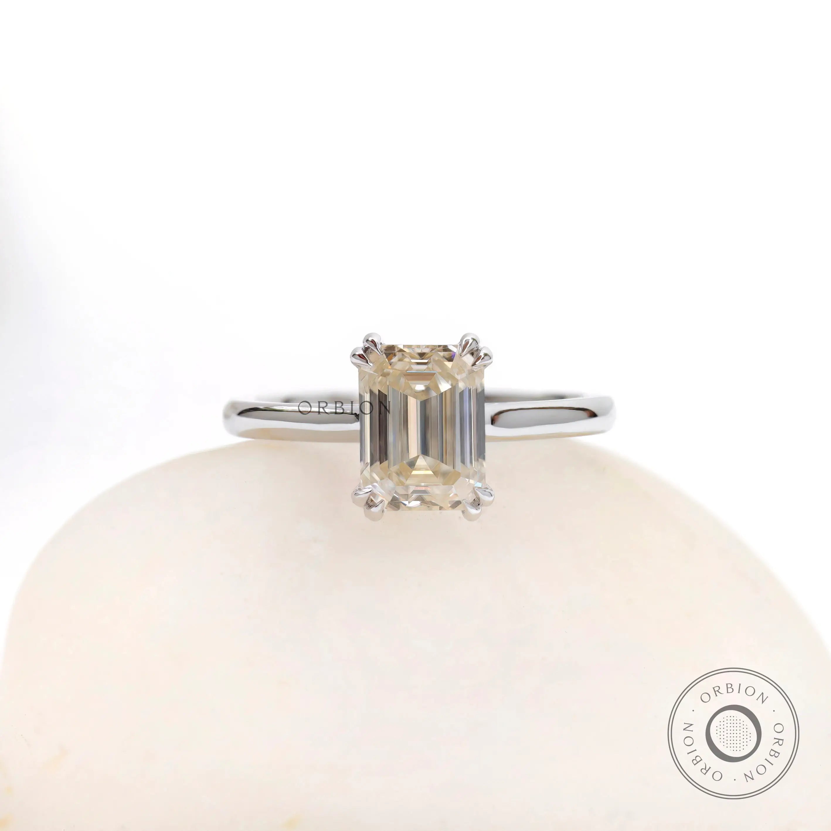 Front view emerald cut moissanite solitaire ring on white stone in white gold