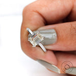 Held top view closeup of emerald cut moissanite solitaire with claw prongs