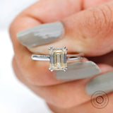Held straight-on front view showcasing emerald cut clarity and step sparkle