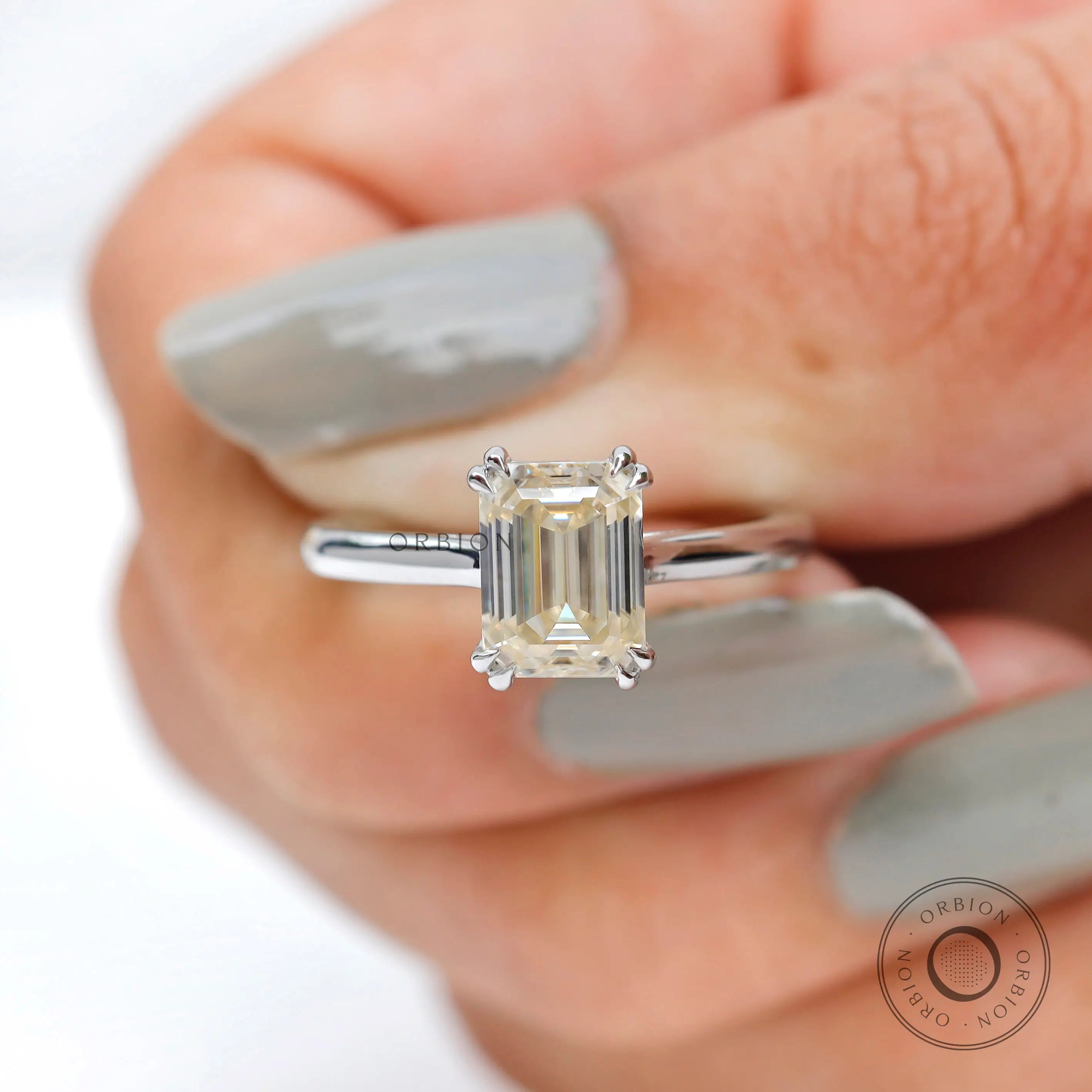 Held straight-on front view showcasing emerald cut clarity and step sparkle
