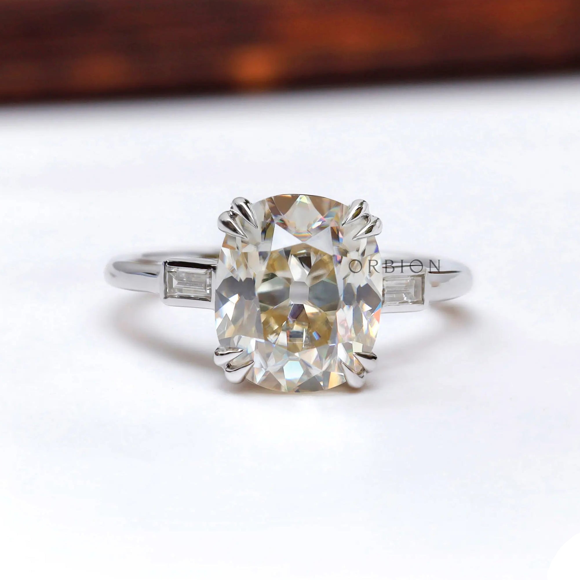 Front view of elongated cushion moissanite three stone ring in white gold.