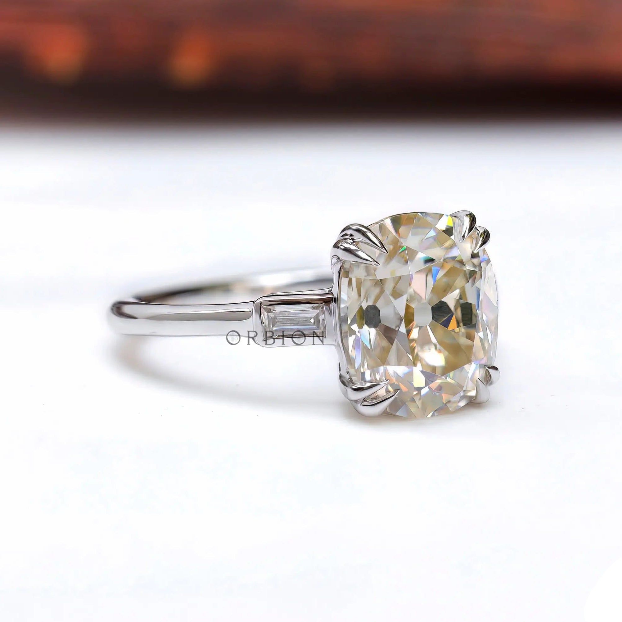 Angled view of cushion moissanite with baguette sides in white gold.