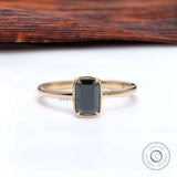 Bezel set black green emerald cut moissanite solitaire in yellow gold.