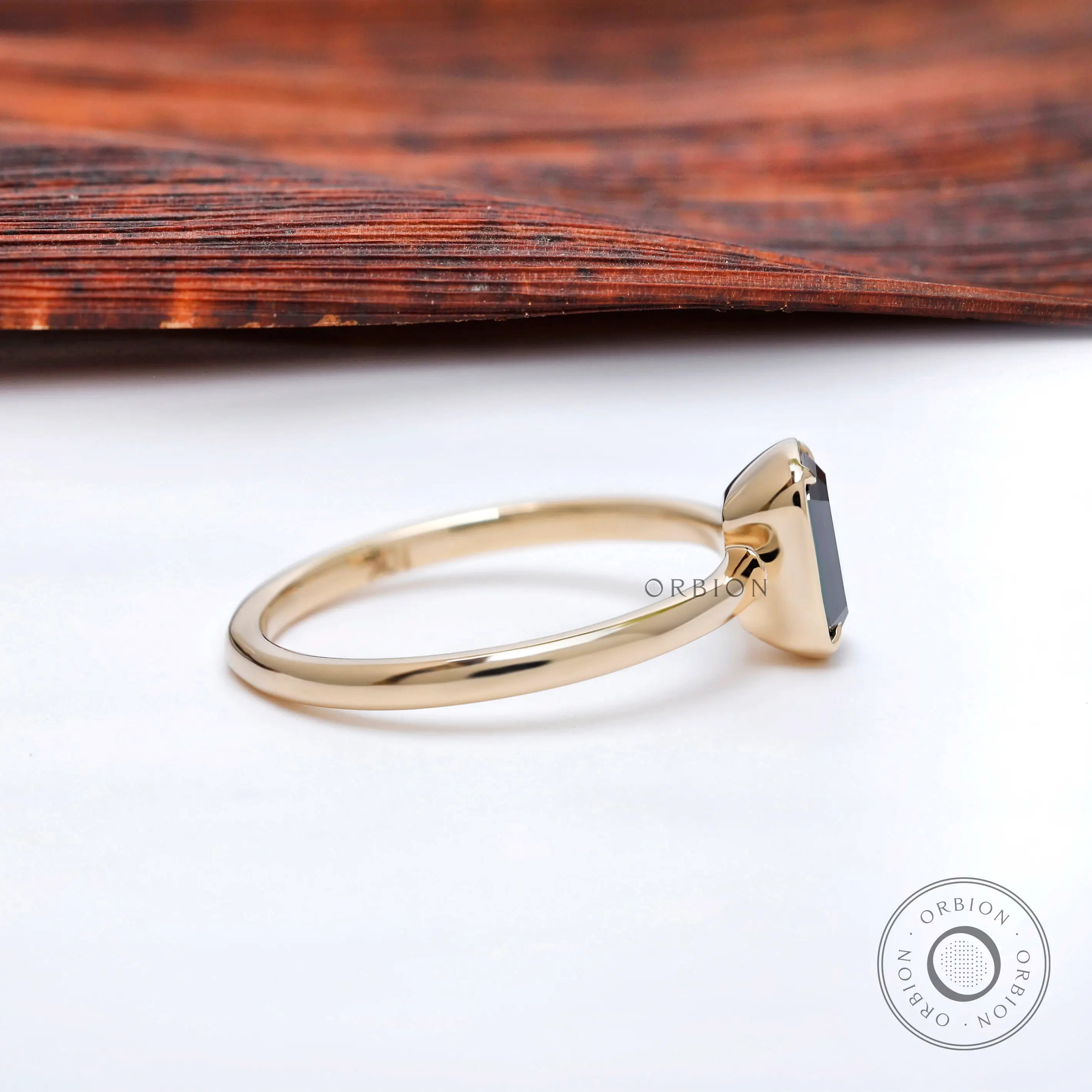 Low profile bezel setting on slim polished yellow gold band.
