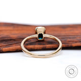 Open back bezel showing black green moissanite and gold shank.