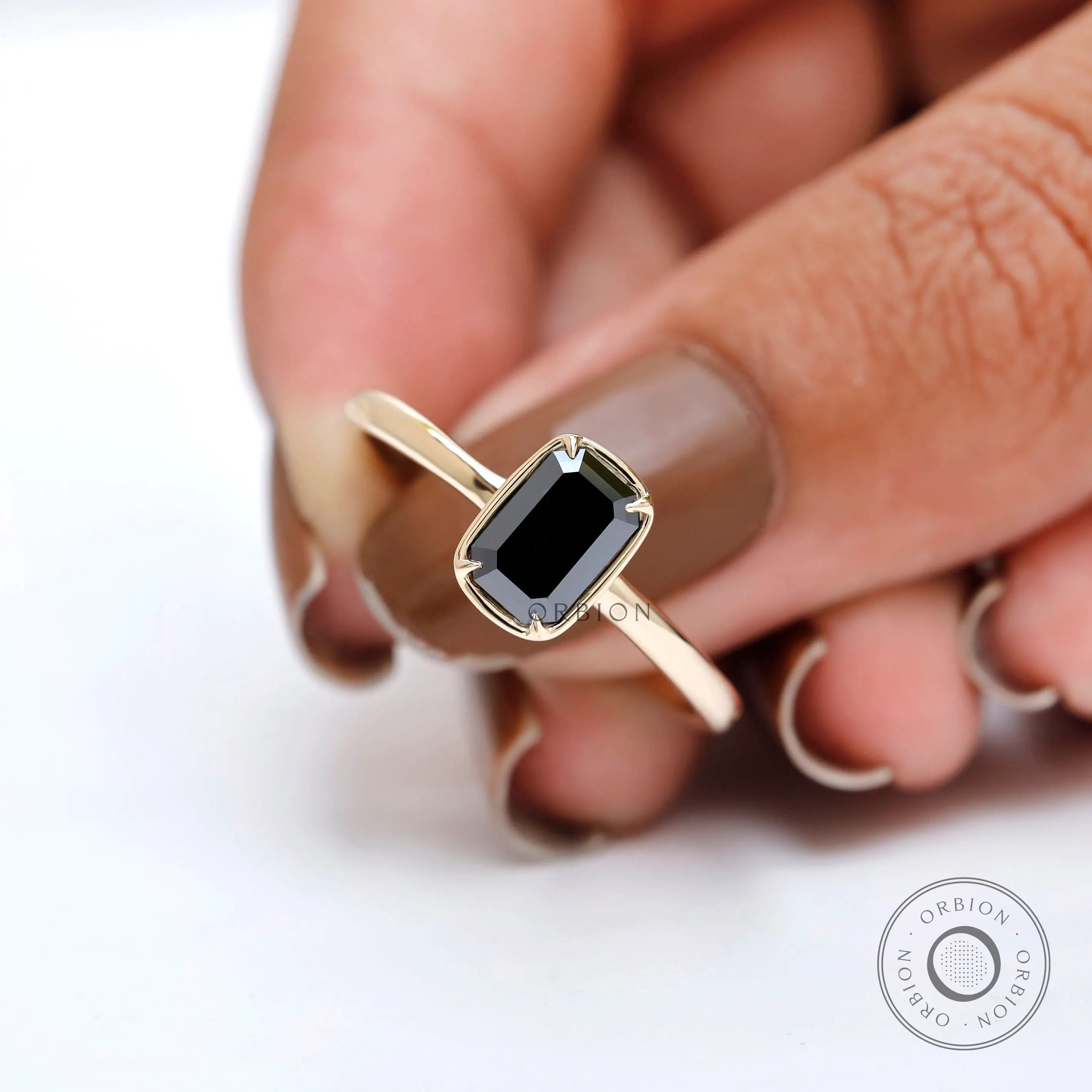 Minimal bezel solitaire ring with black green stone on fingertips.