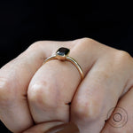 Bezel set emerald cut black green moissanite ring worn on hand.