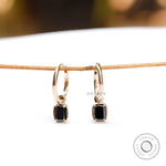Emerald cut dark green moissanite drop earrings glossy yellow gold close up