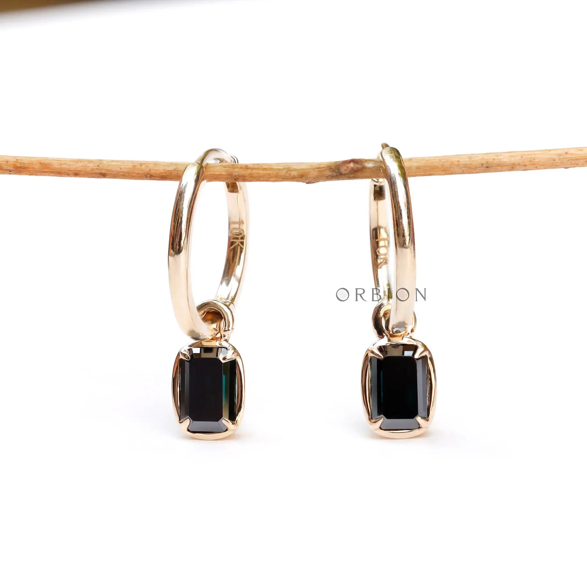 Emerald cut dark green moissanite drop earrings glossy yellow gold close up